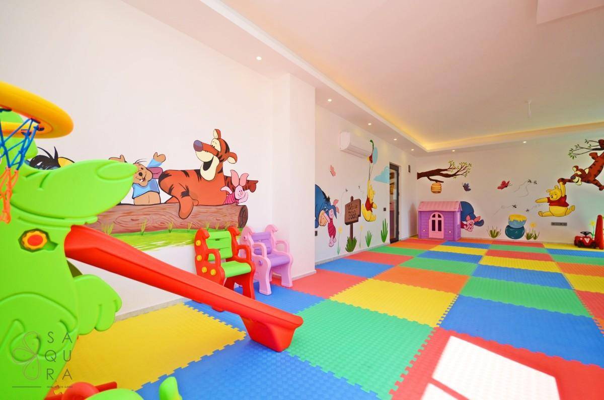 Farbenfrohes Kinderspielzimmer mit weichen Bodenmatten, Rutsche und fröhlichen Wandbildern.