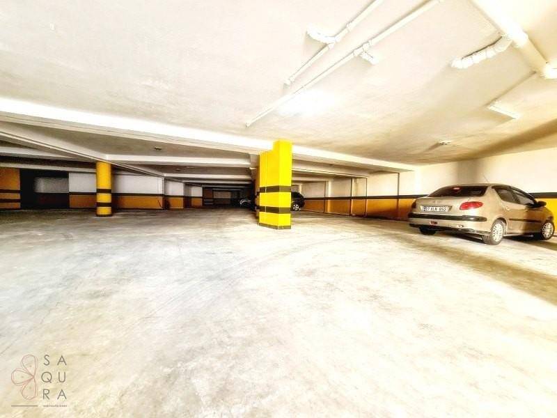 Geräumige Tiefgarage mit markierten Parkplätzen, gelben Säulen und sichtbaren Leitungen an der Decke.
