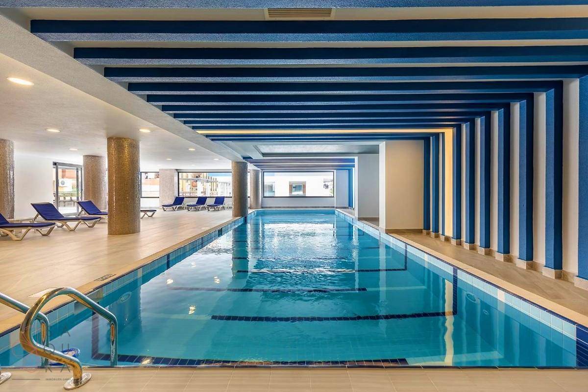 Großer Innenpoolbereich mit blauen Akzenten und Liegestühlen für Entspannung und Wellness.