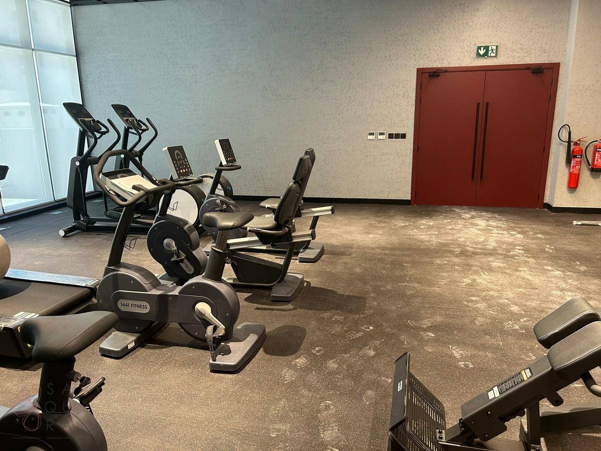 Fitnessraum mit verschiedenen Cardio-Geräten und Hantelbänken.