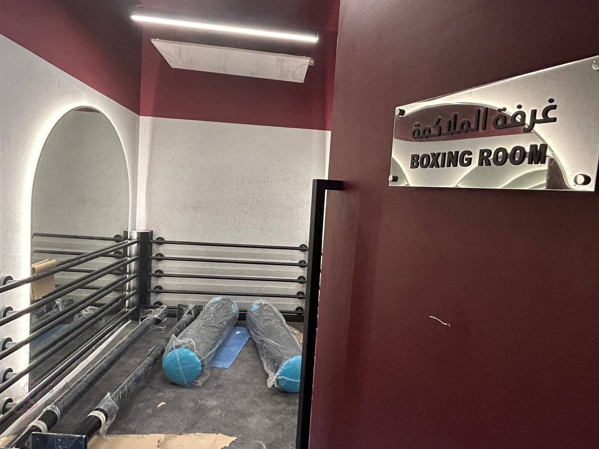Eingangsbereich zu einem Boxraum mit Ring und Sportgeräten.
