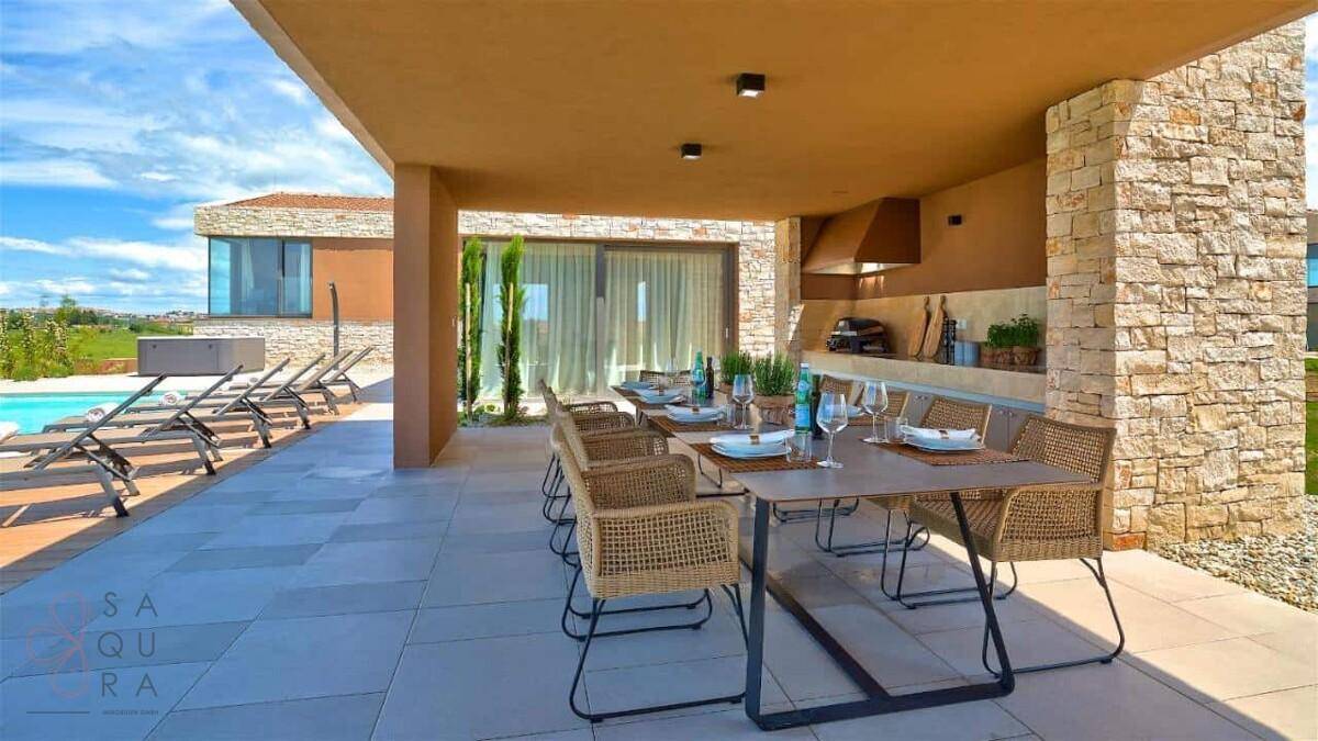 Einladender überdachter Essbereich im Freien mit gedecktem Tisch und Blick auf die Poolterrasse.