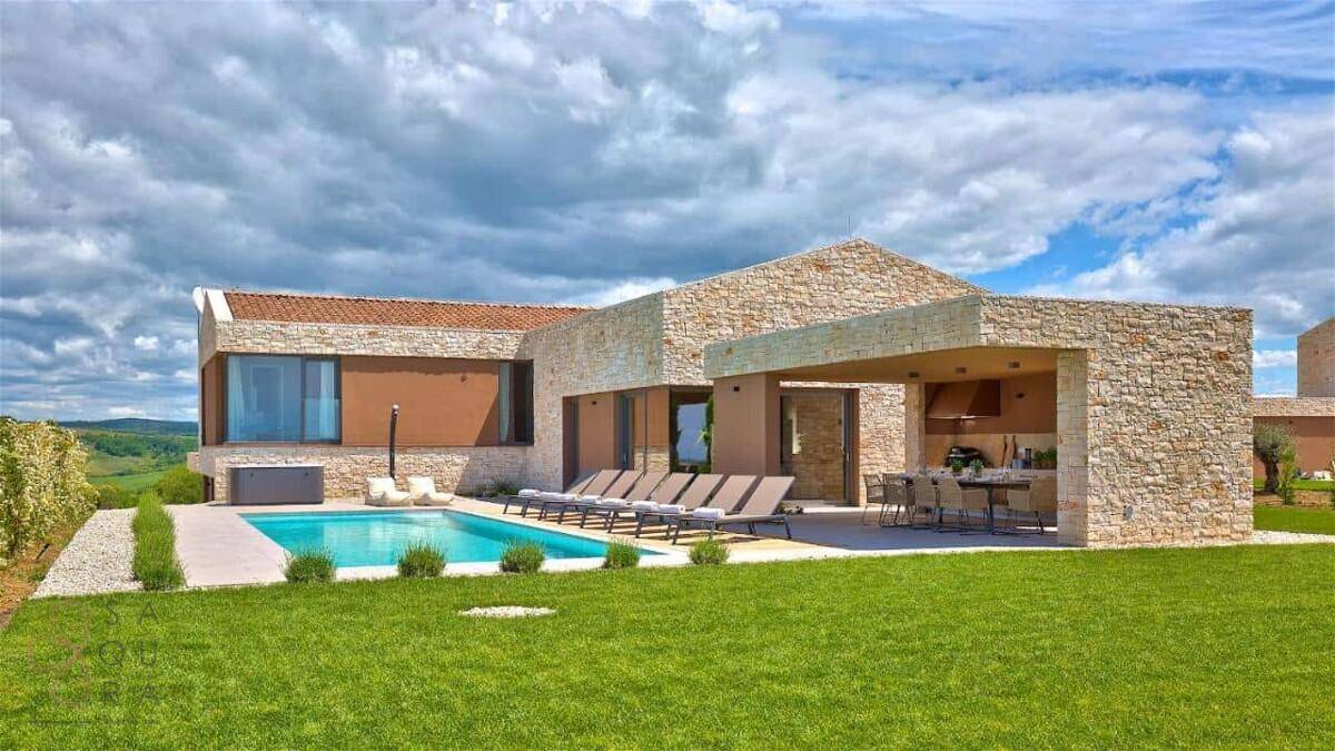 Luxuriöse Villa mit Steinfassade, großem Swimmingpool, Sonnenliegen und überdachtem Essbereich.