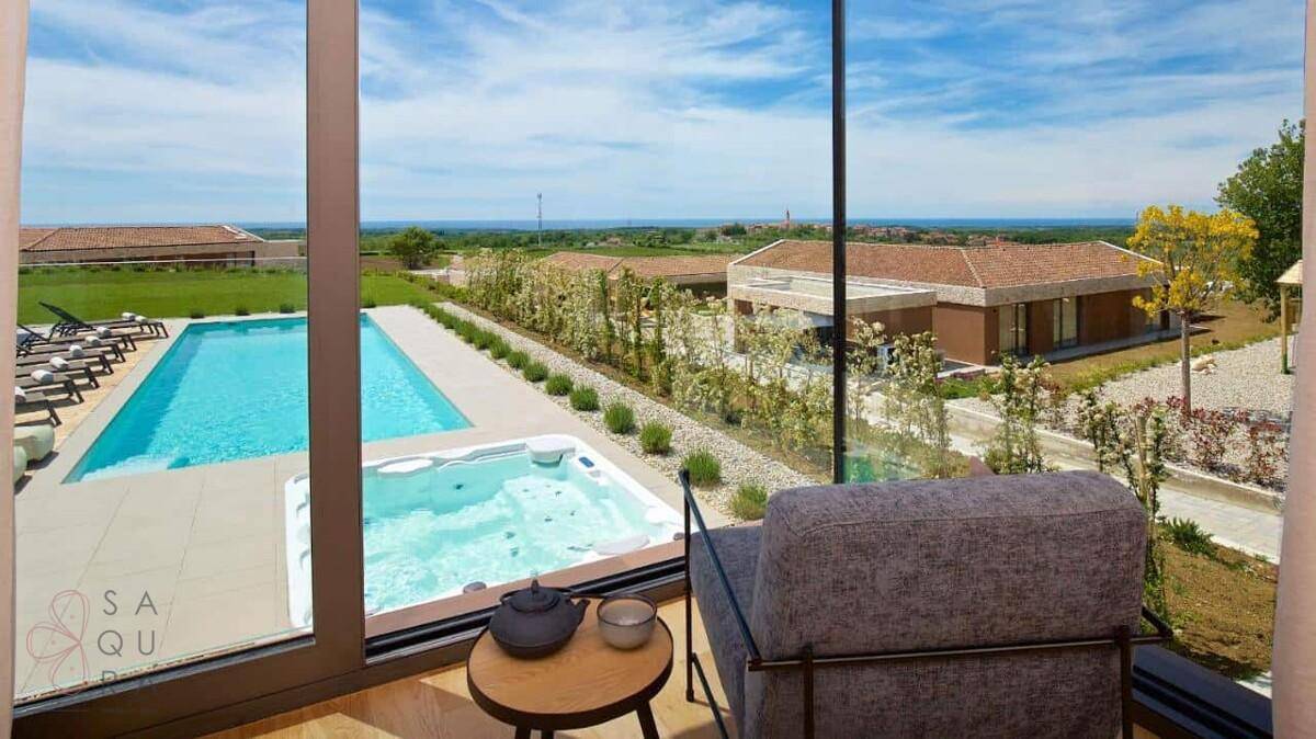 Gemütlicher Innenbereich mit Sessel und weitem Blick auf den Pool, Whirlpool und das Meer.