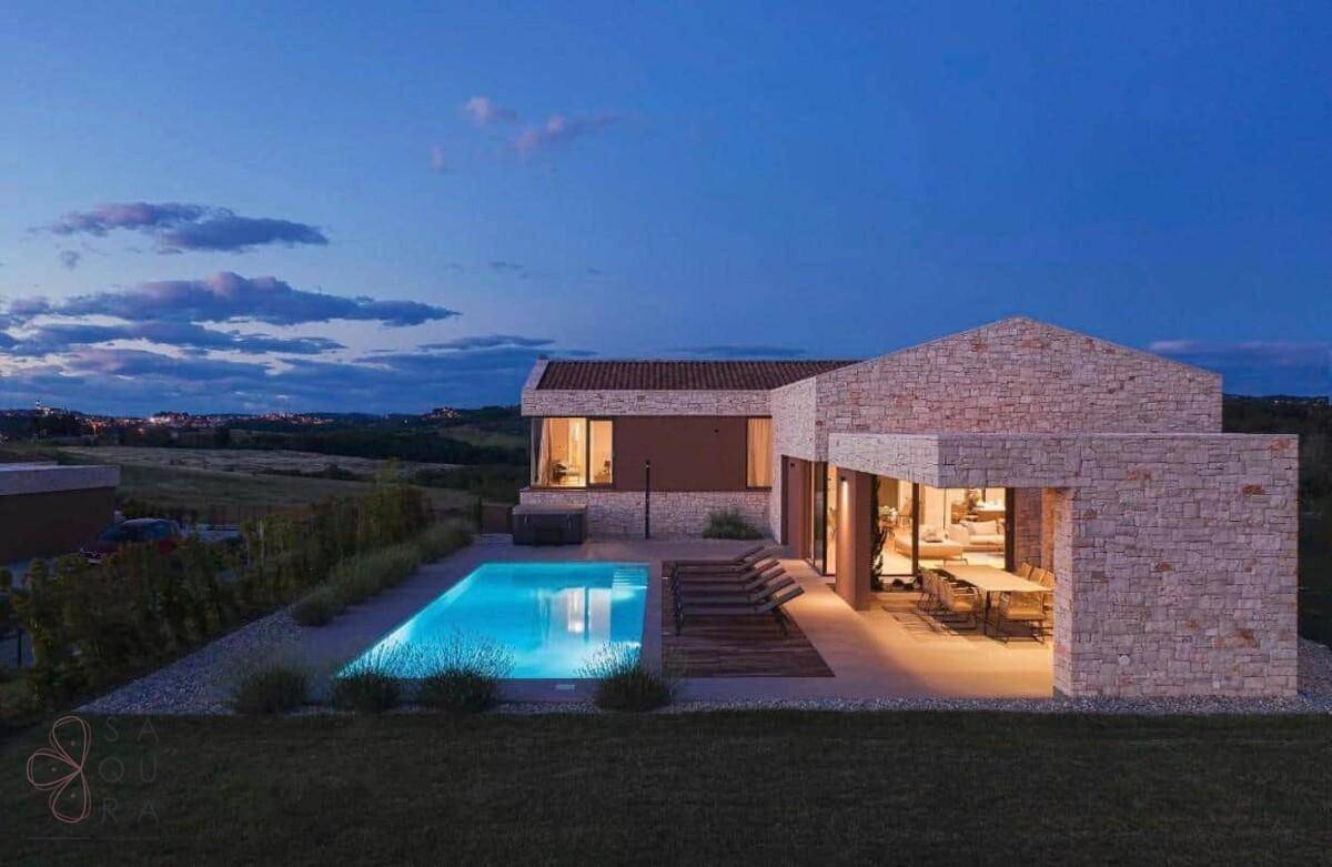 Die moderne Villa bei Sonnenuntergang mit beleuchtetem Pool und stimmungsvoller Außenbeleuchtung.