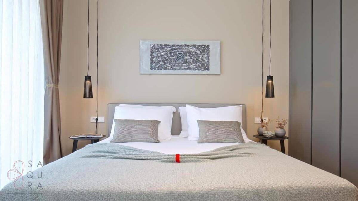 Modernes Schlafzimmer mit Doppelbett, stilvollen Hängelampen und großem Fenster mit Vorhängen.