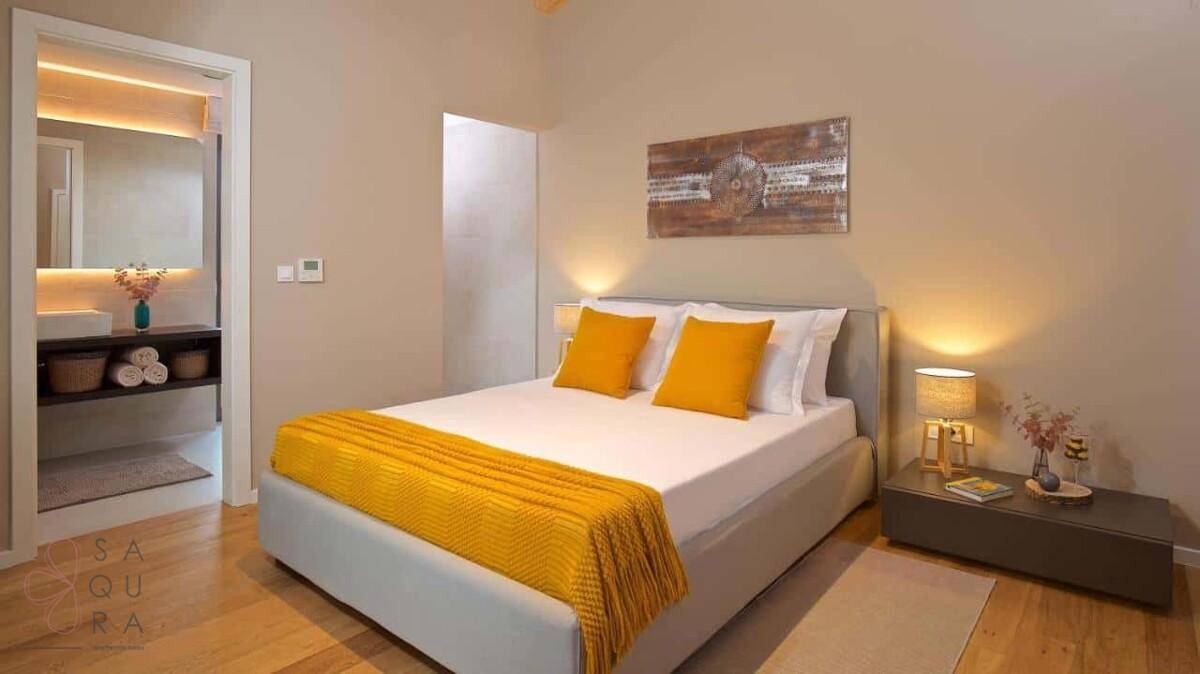 Gemütliches Schlafzimmer mit gelben Akzenten und direktem Zugang zu einem modernen Badezimmer.
