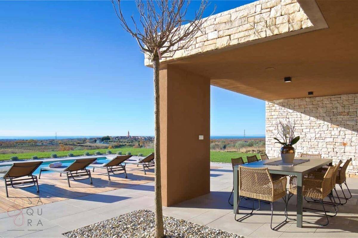 Überdachte Terrasse mit Esstisch und Poolblick, umgeben von mediterraner Landschaft und Meer.