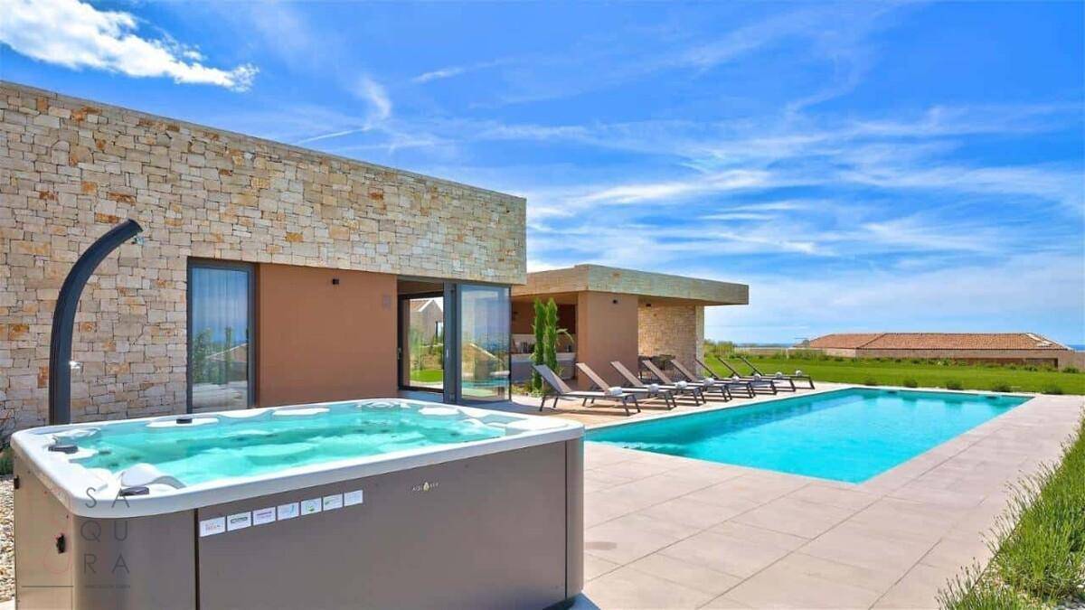 Moderner Whirlpool neben dem Swimmingpool mit Blick auf die Villa und die umliegende Natur.