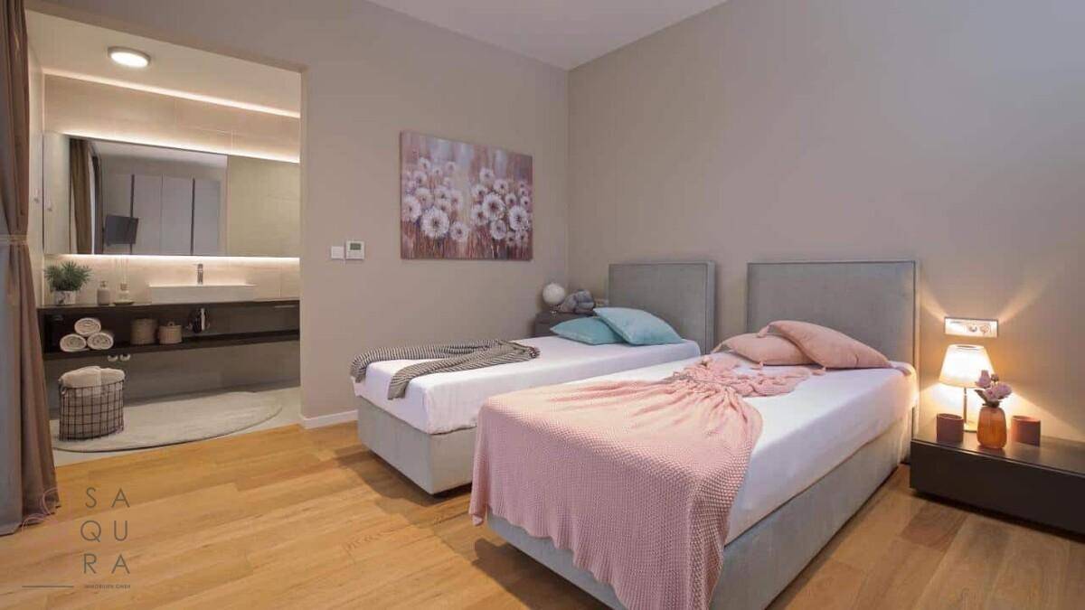 Komfortables Schlafzimmer mit zwei Einzelbetten und direktem Zugang zu einem modernen Badezimmer.