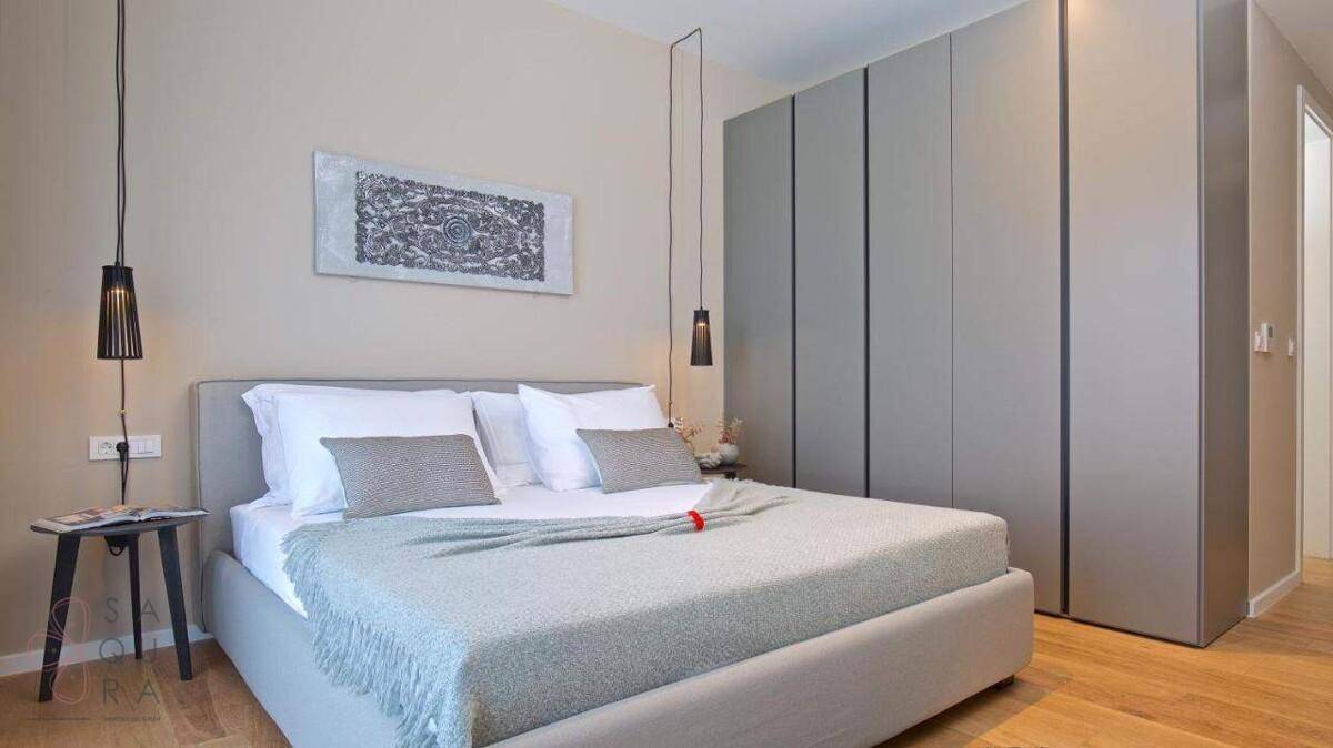 Modernes Schlafzimmer mit integriertem Kleiderschrank, Doppelbett und stilvollen Hängelampen.
