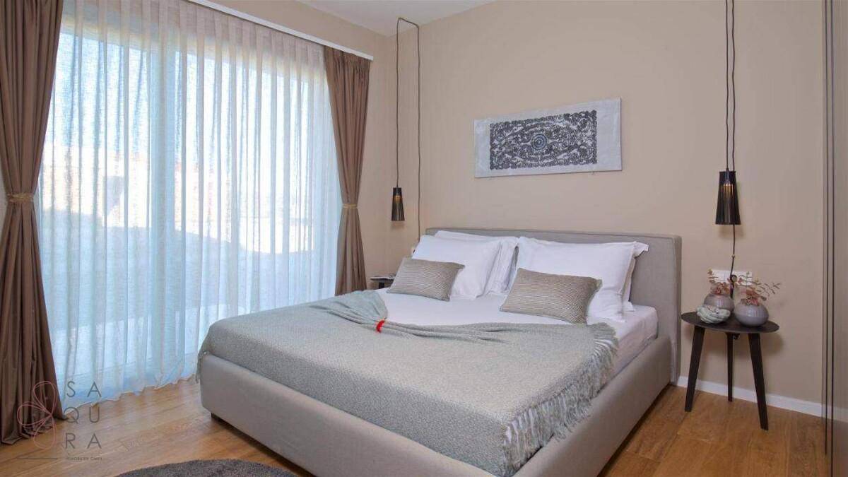 Helles Schlafzimmer mit großem Fenster, das viel Tageslicht hereinlässt, und modernem Doppelbett.