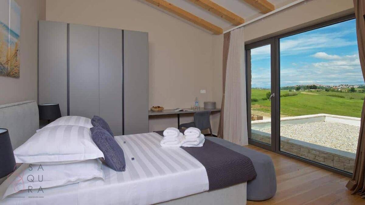 Helles Schlafzimmer mit großem Bett, Kleiderschrank und Zugang zu einer Terrasse mit Weitblick.