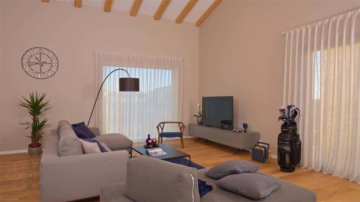 Gemütliches Wohnzimmer mit bequemer Couch, Fernseher und großen Fenstern für viel Helligkeit.
