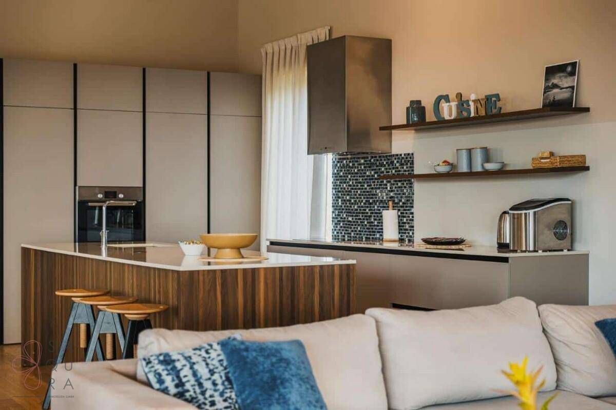 Moderne Küche mit Kochinsel, integrierten Geräten und stilvollem Mosaik-Spritzschutz.