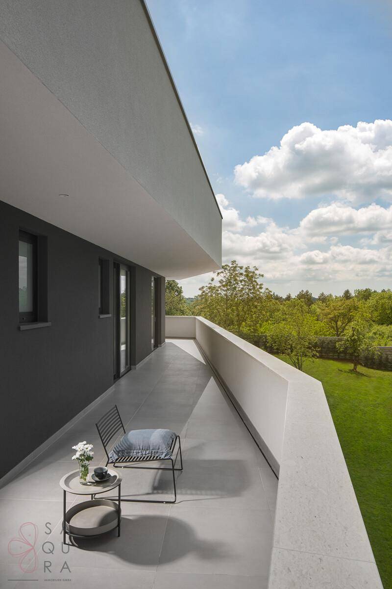Langer, schmaler Balkon mit Sitzgelegenheit und weitem Blick über die grüne Landschaft.