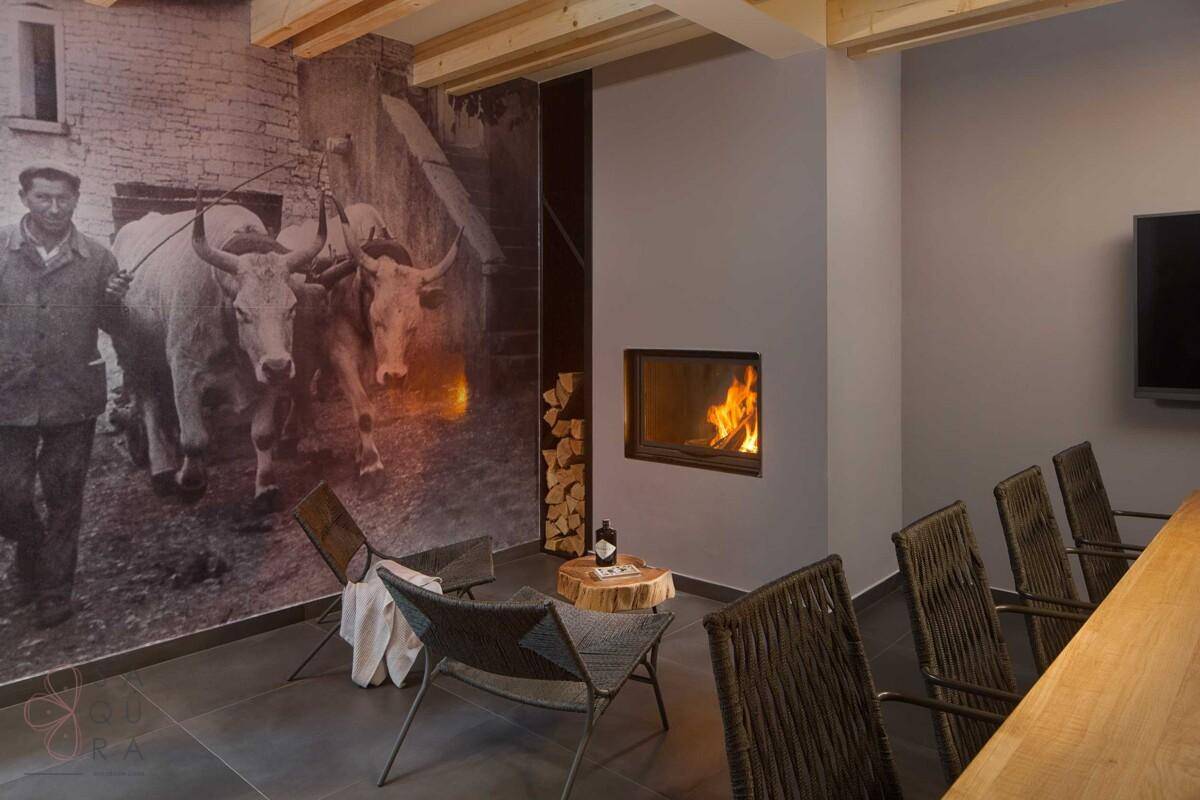 Gemütlicher Wohnbereich mit modernem Kamin, Holzlager und rustikaler Wandtapete.