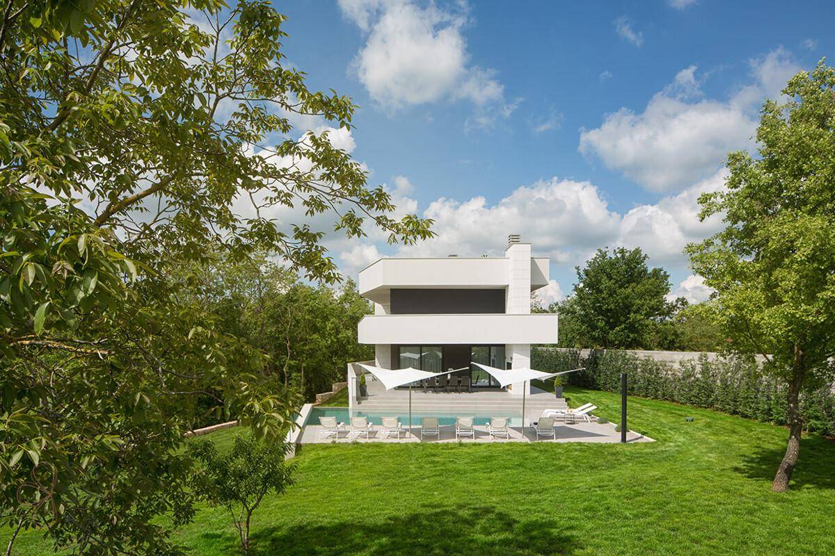Moderne Villa mit Poolbereich und weitläufigem Garten, umgeben von üppiger grüner Natur.