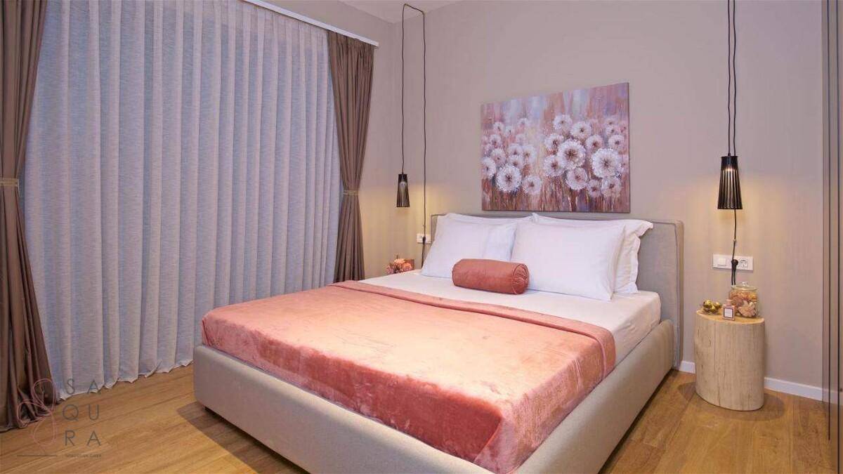 Modernes Schlafzimmer mit Doppelbett, rosa Bettüberwurf und Kunstwerk über dem Kopfteil.