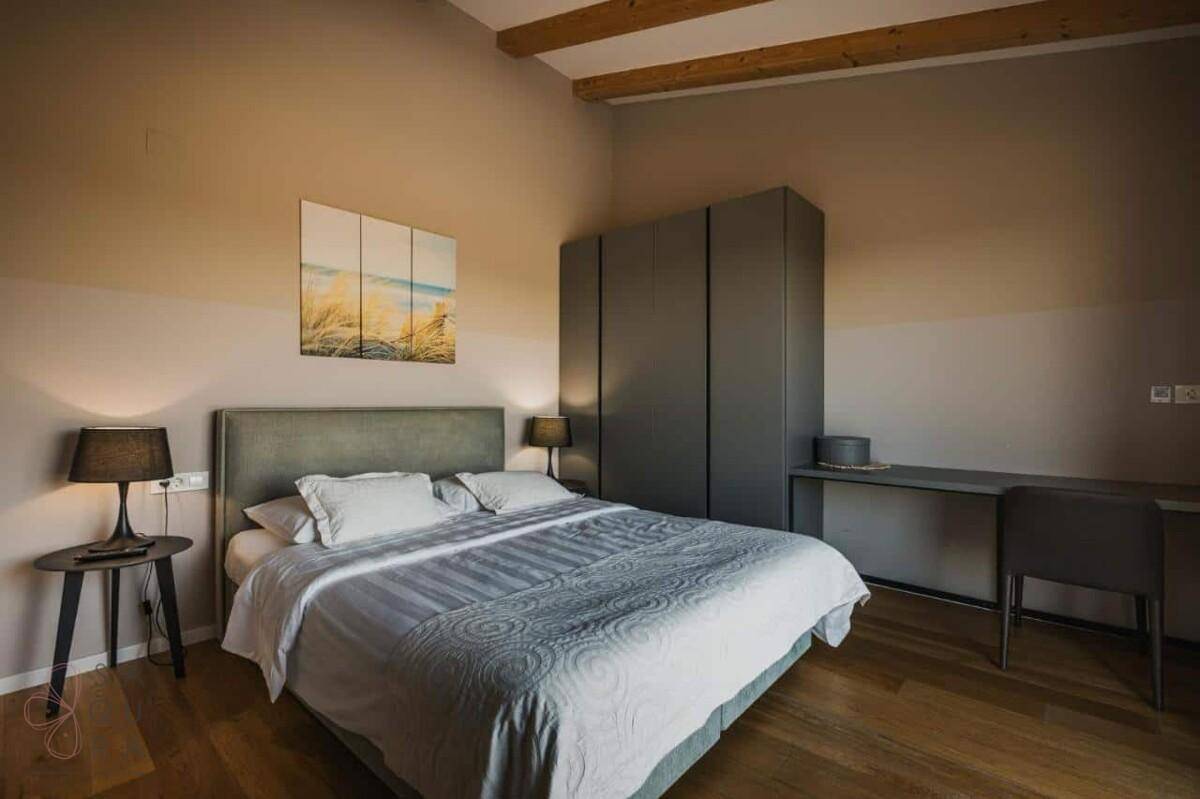 Geräumiges Schlafzimmer mit Holzbalkendecke, Schreibtisch und großem integriertem Kleiderschrank.