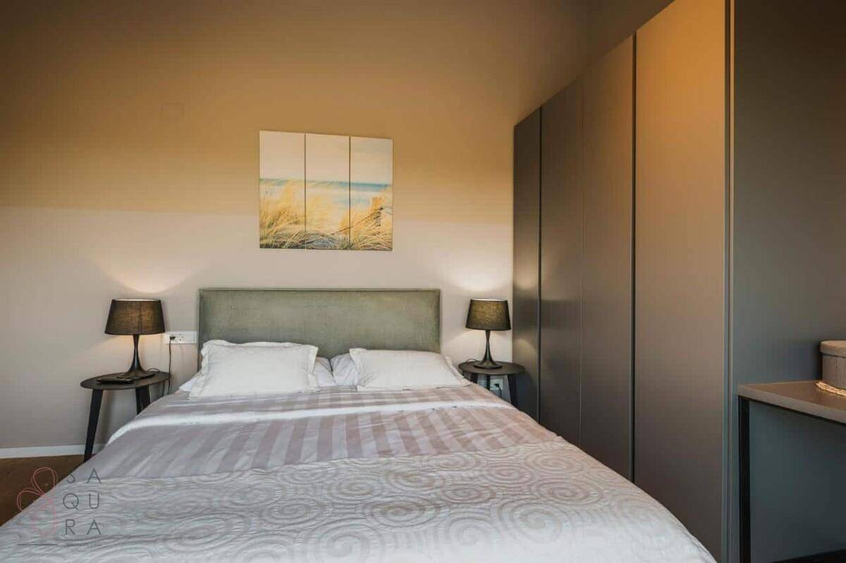 Modernes Schlafzimmer mit Doppelbett, Nachttischen und einem großen, integrierten Kleiderschrank.