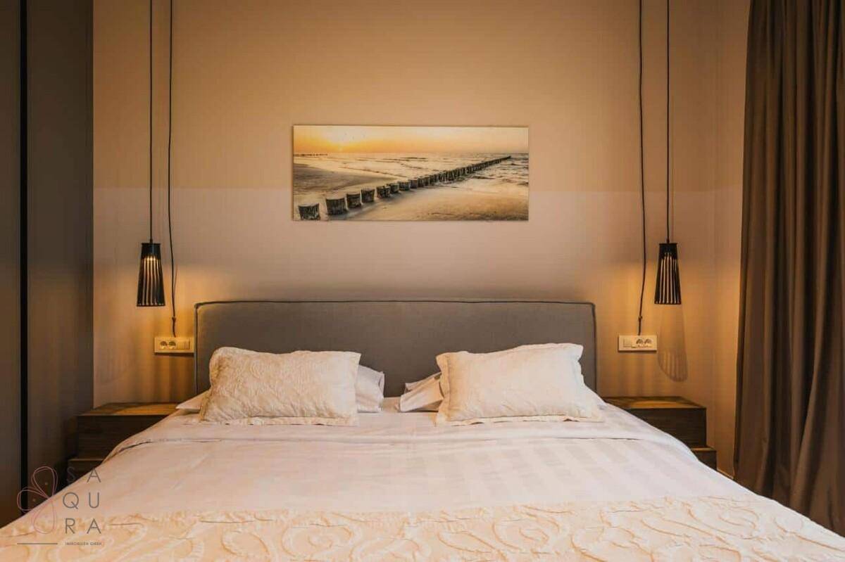 Komfortables Schlafzimmer mit Doppelbett, Nachttischen und einem stimmungsvollen Bild über dem Bett.