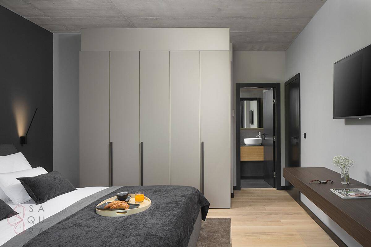 Schlafzimmer mit integriertem Kleiderschrank und Zugang zu einem modernen Badezimmer.