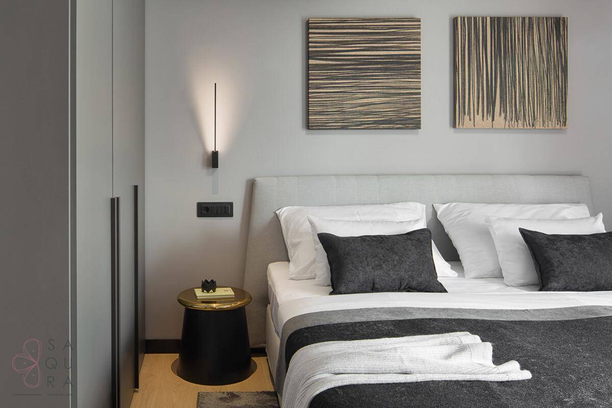 Modernes Schlafzimmer mit gepolstertem Bett, minimalistischer Einrichtung und Kunstwerken an der Wand.