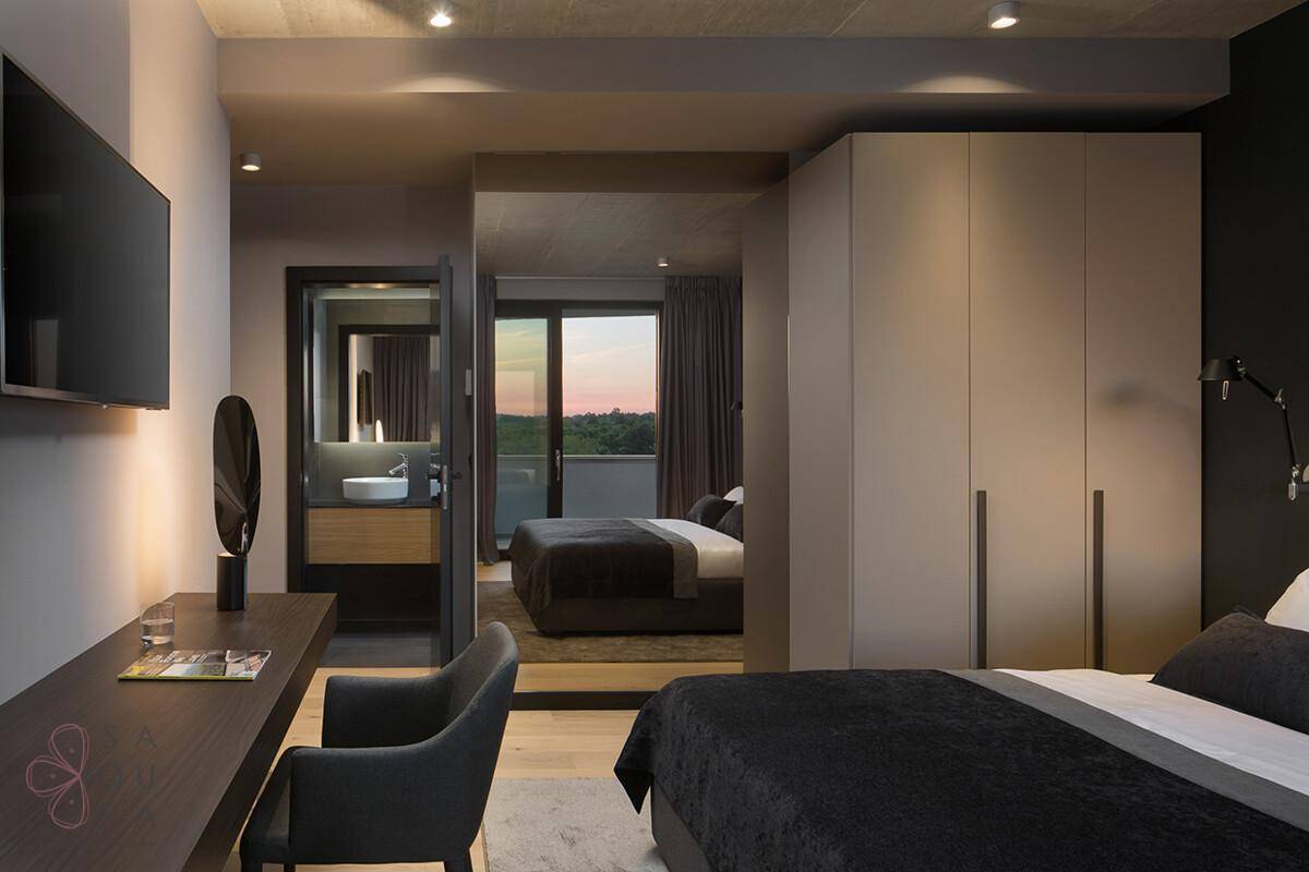 Modernes Schlafzimmer mit integriertem Bad und Blick auf einen weiteren Schlafbereich mit Balkonzugang.
