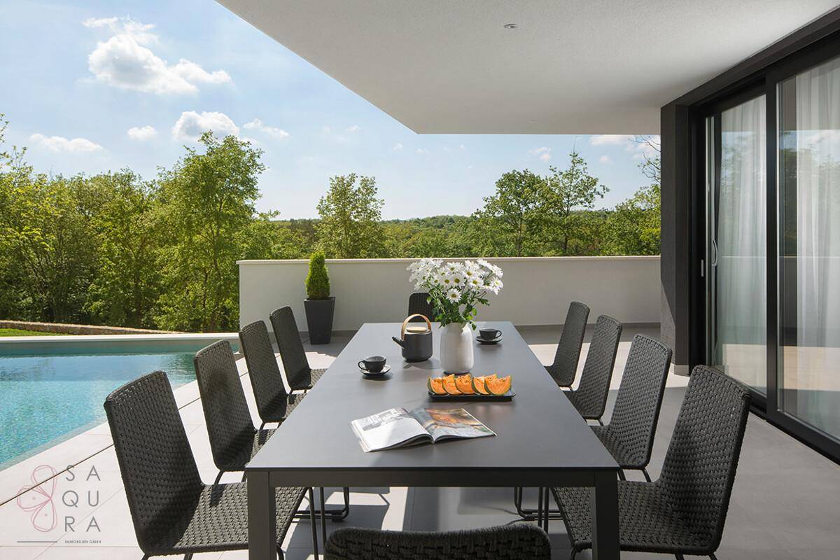 Großer Essbereich im Freien mit modernem Tisch und Stühlen neben dem Pool.