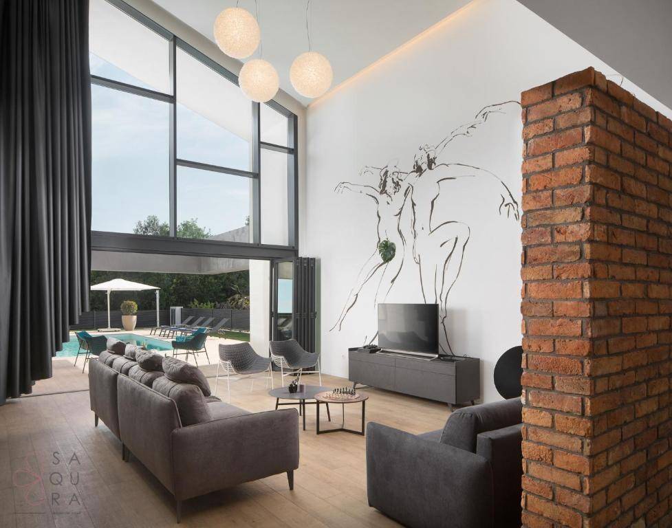 Helles Wohnzimmer mit hohen Fenstern, Blick auf den Pool und moderner Einrichtung.
