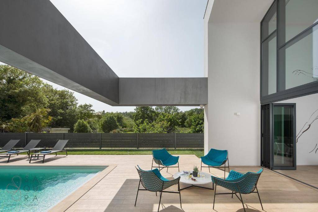 Elegante Terrasse mit modernen blauen Sesseln und Blick auf den Pool und die grüne Umgebung.
