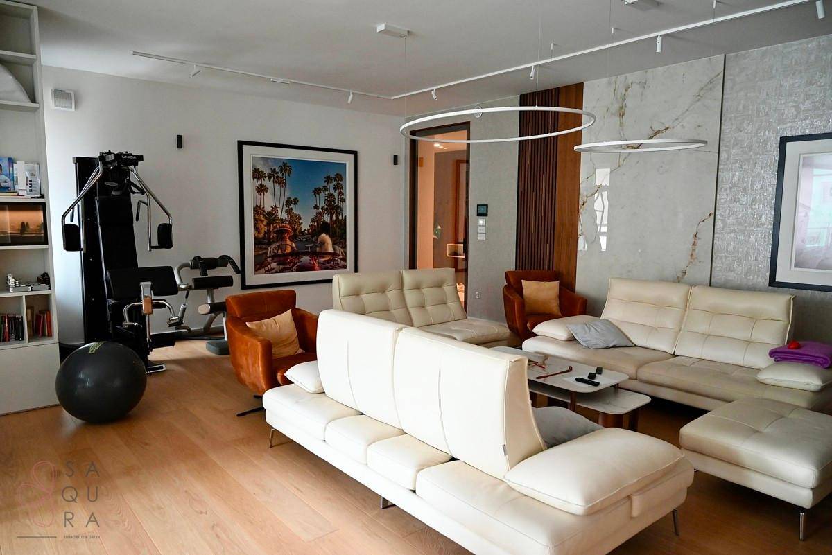 Geräumiges Wohnzimmer mit bequemen Sofas, Holzboden und integriertem Fitnessbereich.