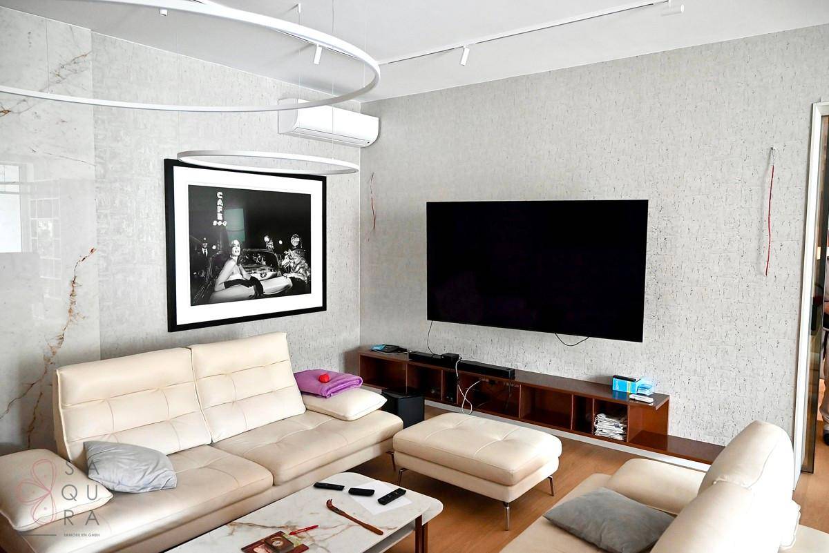 Gemütliches Wohnzimmer mit beigem Sofa, großem Fernseher und moderner Dekoration.