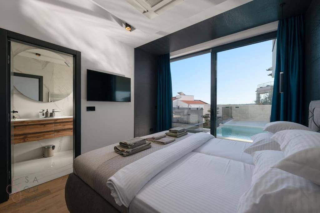 Schlafzimmer mit Panoramablick auf den Pool und die Umgebung, mit angrenzendem modernen Badezimmer.