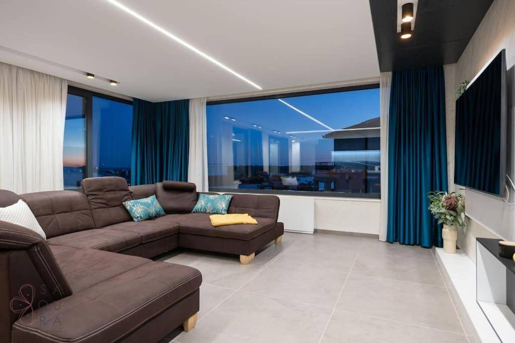 Gemütliches Wohnzimmer mit großem Sofa, Fernseher und weitem Blick durch die Fenster.