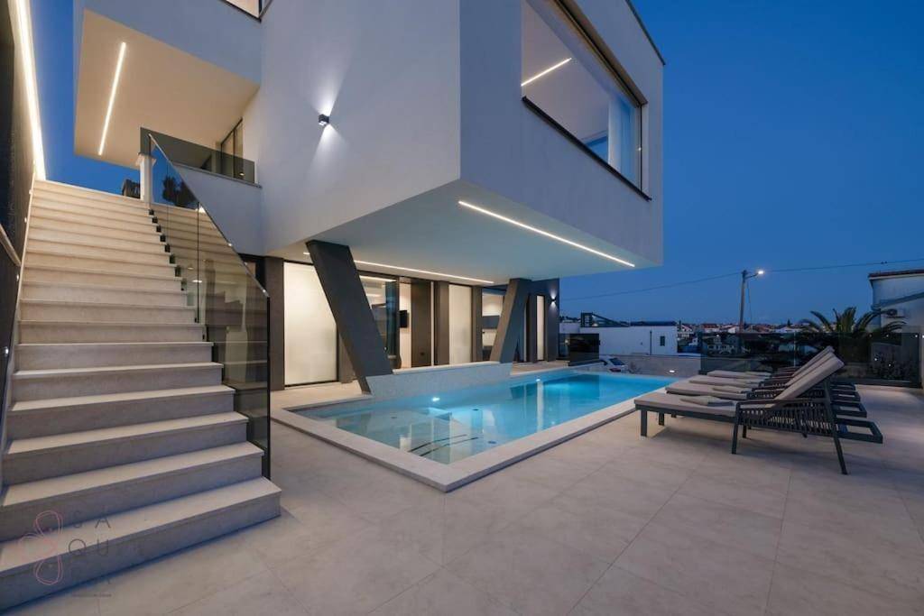 Beleuchteter Poolbereich bei Dämmerung mit moderner Architektur und Treppenaufgang.
