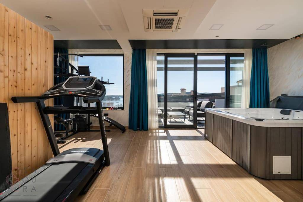 Großer Fitness- und Wellnessbereich mit Laufband, Kraftstation und Whirlpool, mit Terrassenzugang.