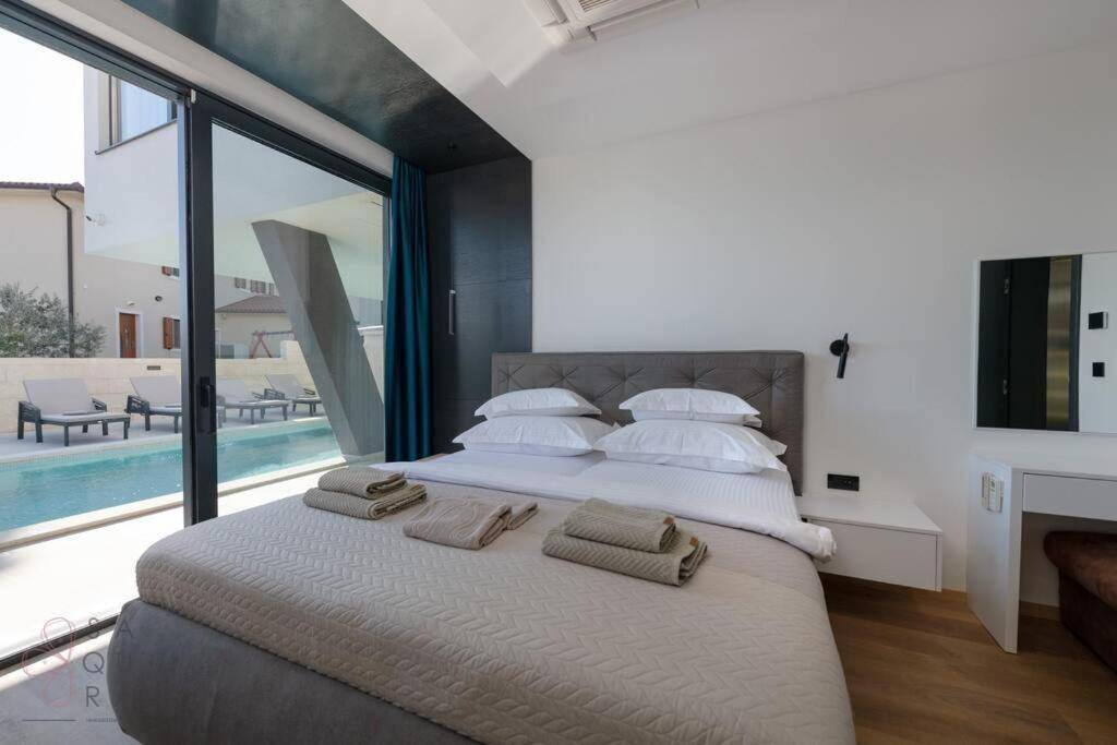 Schlafzimmer mit großen Fenstern und direktem Blick auf den privaten Poolbereich im Freien.