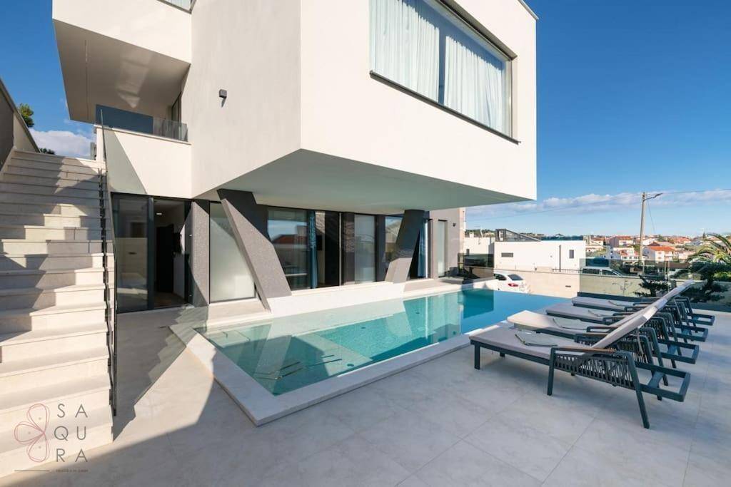 Heller Poolbereich mit Sonnenliegen und Treppe zum oberen Stockwerk der Villa.