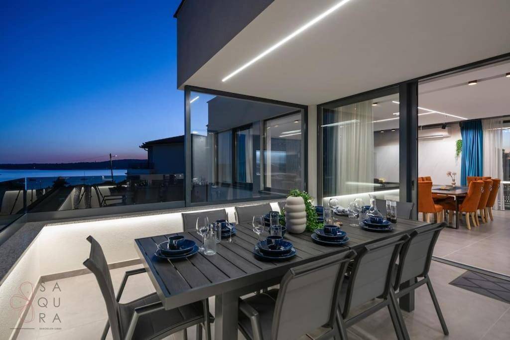 Eleganter Essbereich mit Zugang zur Terrasse und Blick auf das Meer bei Dämmerung.