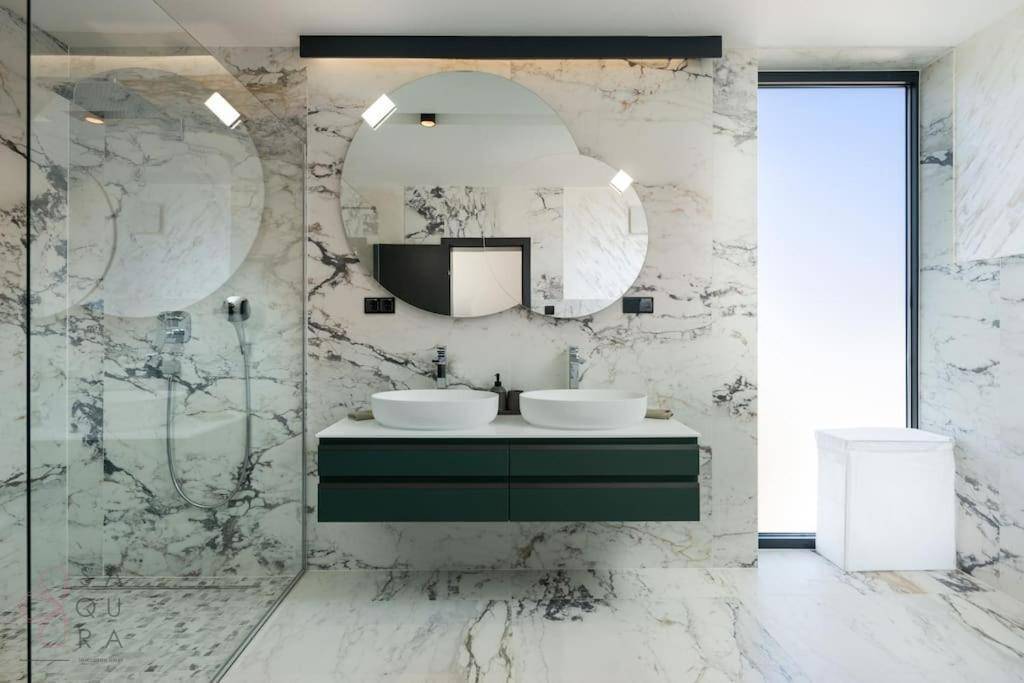 Luxuriöses Badezimmer mit Marmorfliesen, Doppelwaschbecken und einer geräumigen begehbaren Dusche.