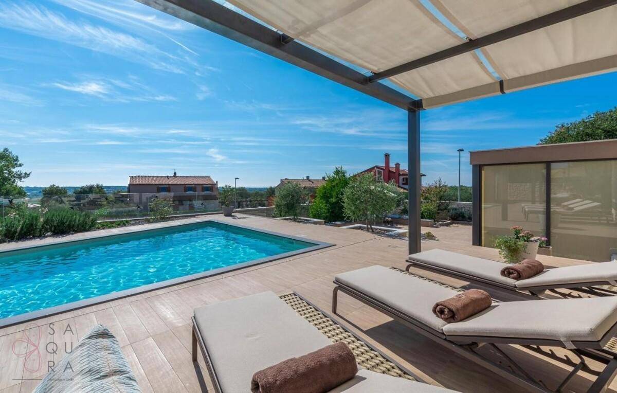 Geräumige Terrasse mit Liegestühlen und weitem Blick über den Pool und die Landschaft.