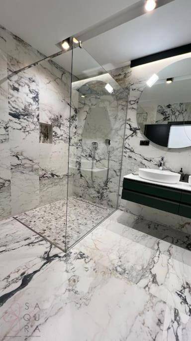 Geräumige begehbare Dusche mit Glasabtrennung und durchgehenden Marmorfliesen im Badezimmer.