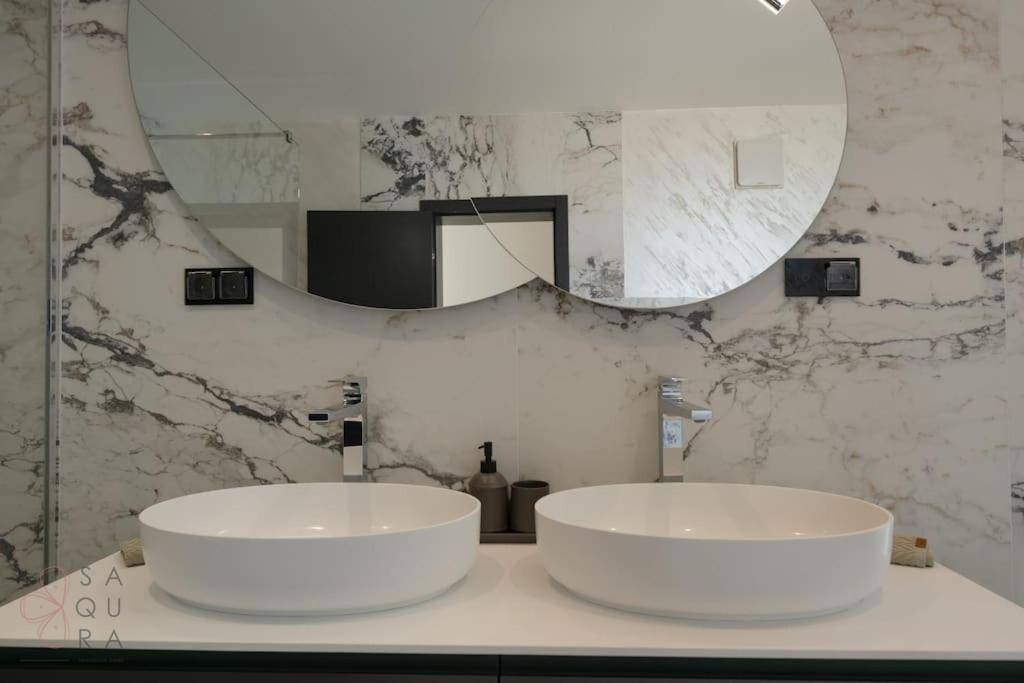 Detailaufnahme der zwei runden Aufsatzwaschbecken und des großen Spiegels im Marmorbadezimmer.