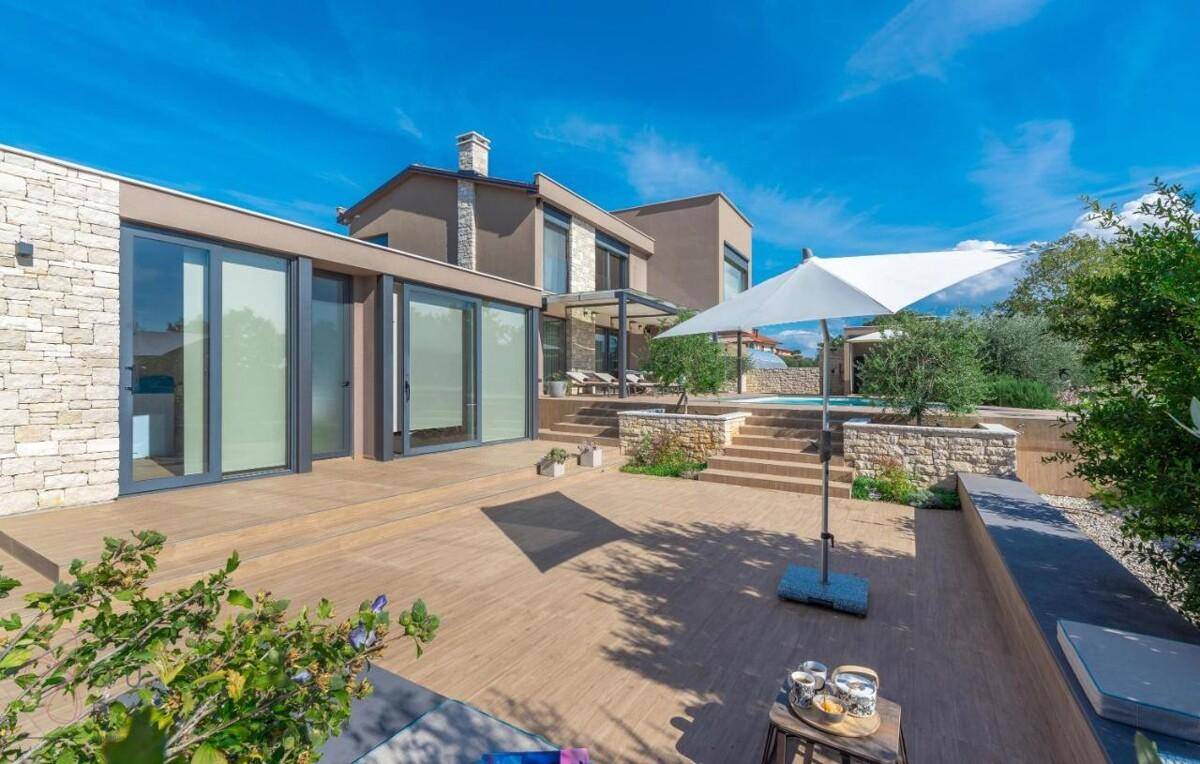 Moderne Villa mit Pool, Sonnenterrasse und gestuftem Gartenbereich mit mediterranen Pflanzen.