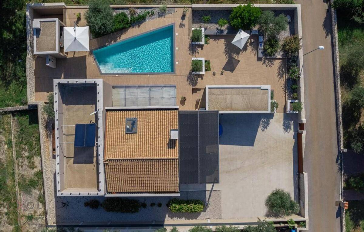 Luftaufnahme der modernen Villa mit Pool, Garten und Parkplatz in der Umgebung.