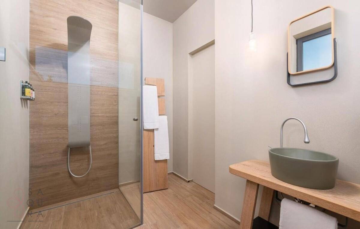 Modernes Badezimmer mit begehbarer Dusche, Holzoptikfliesen und stilvollem Waschbecken.