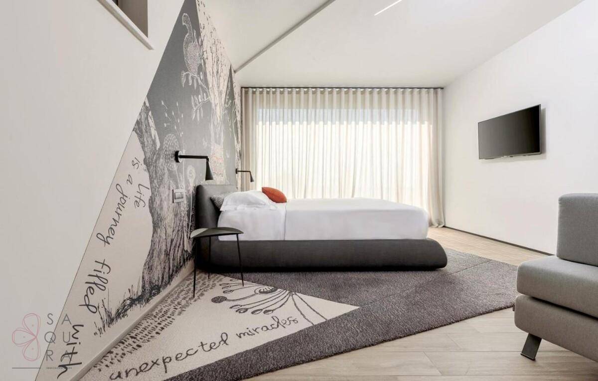 Modernes Schlafzimmer mit einzigartiger Wandgestaltung, großem Bett und Vorhängen für Privatsphäre.