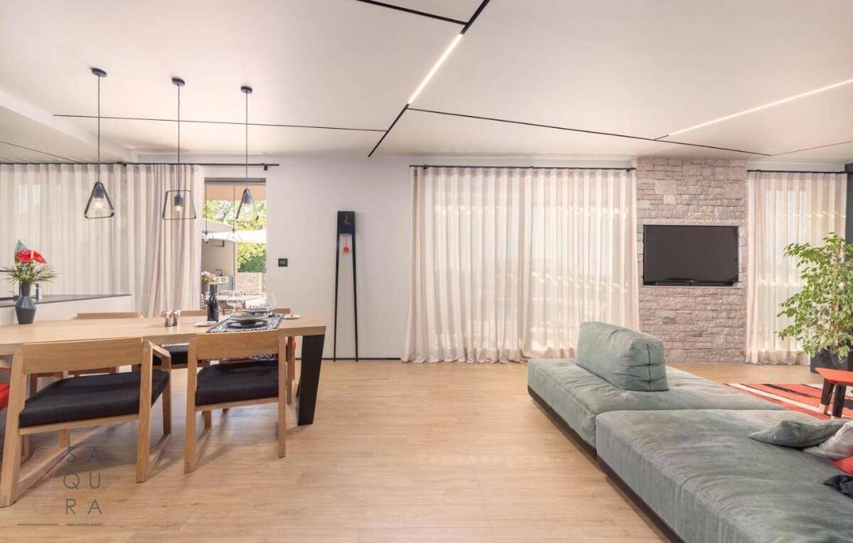 Heller offener Wohn-Essbereich mit bequemer Couch, Holzboden und Steinwandakzent.